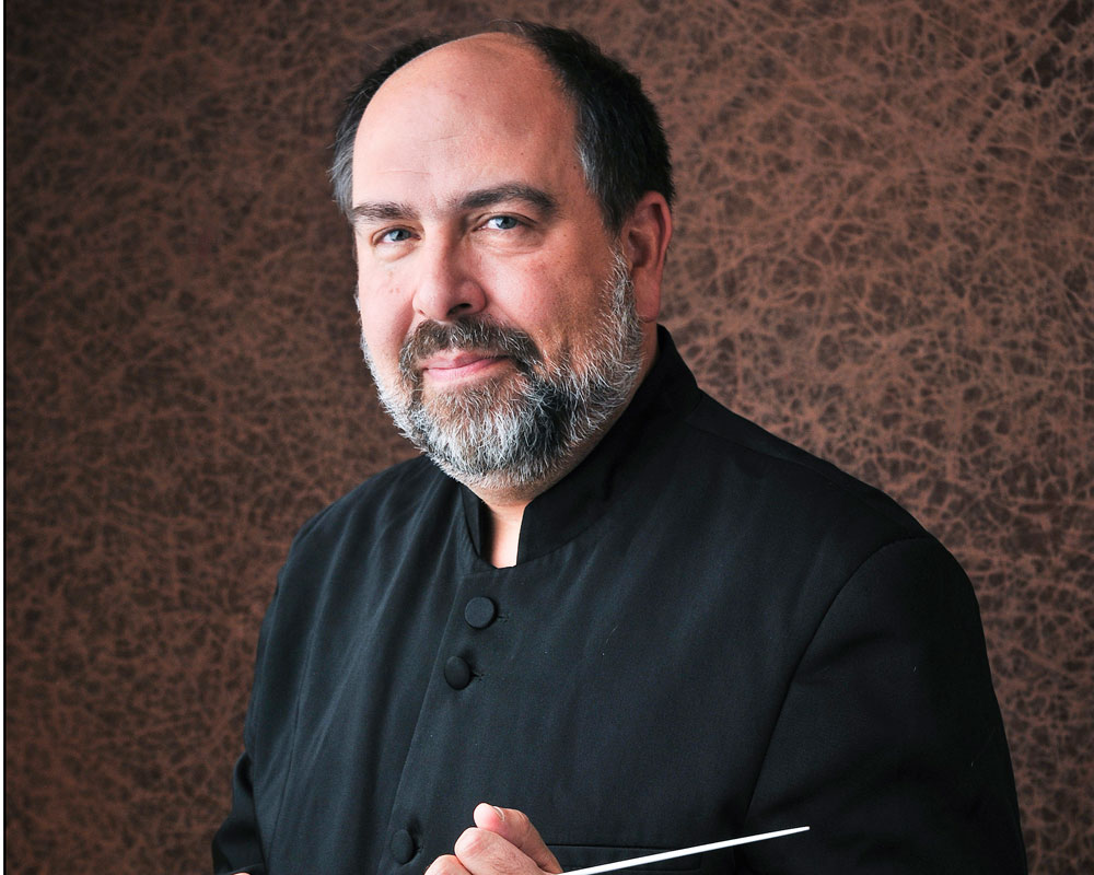 Kenneth Freed Conductor smiling and holding a baton